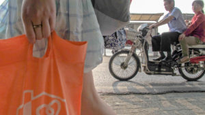Woman carries orange shopping bag