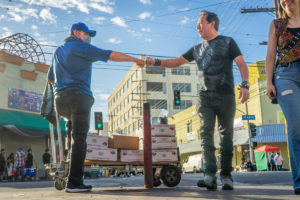 Two men fist bump in the street